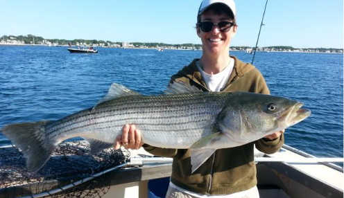 person holding a striped bass they caught aboard the Beth Ann