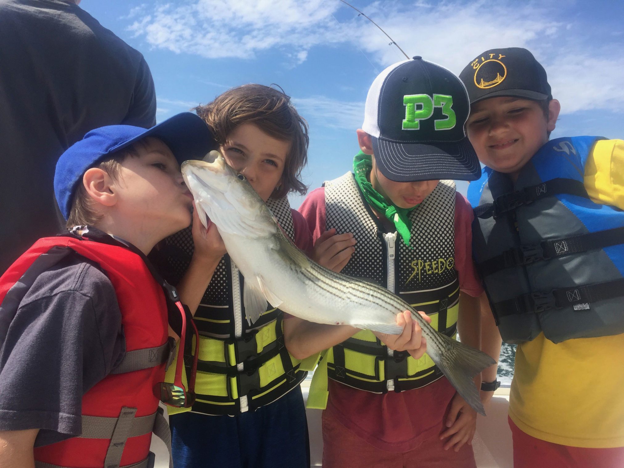Group of kids kissing a striped bass caught in Provincetown