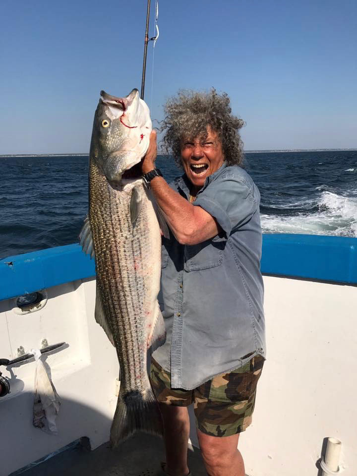 Person holding a large striped bass caught on The Beth Ann during a fishing charter in Provincetown