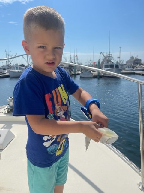 Small boy holding fish he caught with Beth Ann Carters at Provincetown Marina