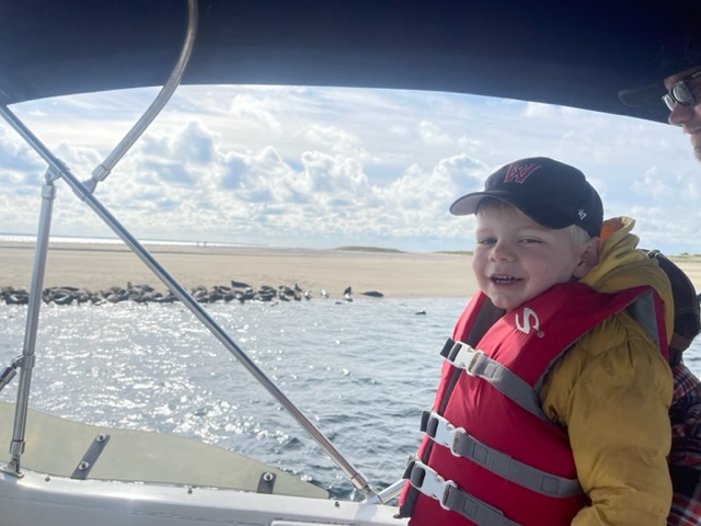 Smiling boy in lifejacket watching seals on shore from Beth Ann Carters ship