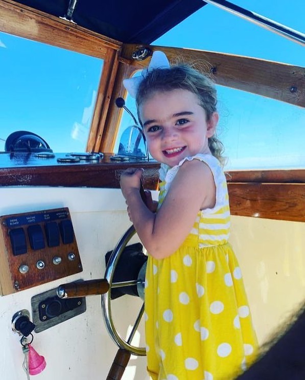 Smiling girl holds onto steering wheel aboard Beth Ann Carters
